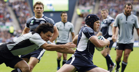 Simon Webster evading the grips of an All Black