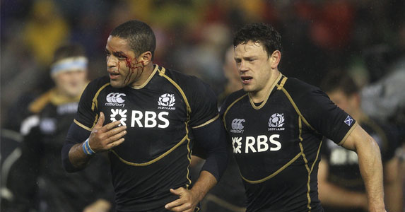 Head wound: Scotland's Joe Ansbro is escorted off the pitch after a painful clash of heads