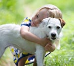 young child cuddles her dog